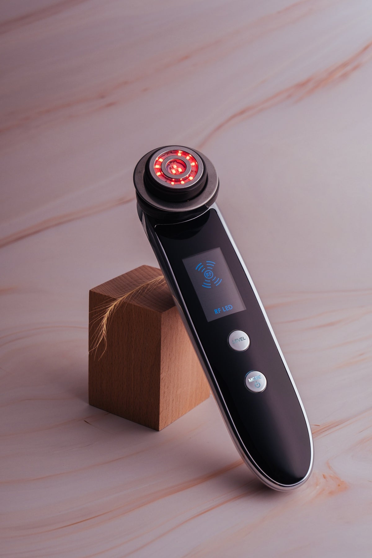 Lunerra RF Glow Wand resting on a wooden block with its red LED head lit